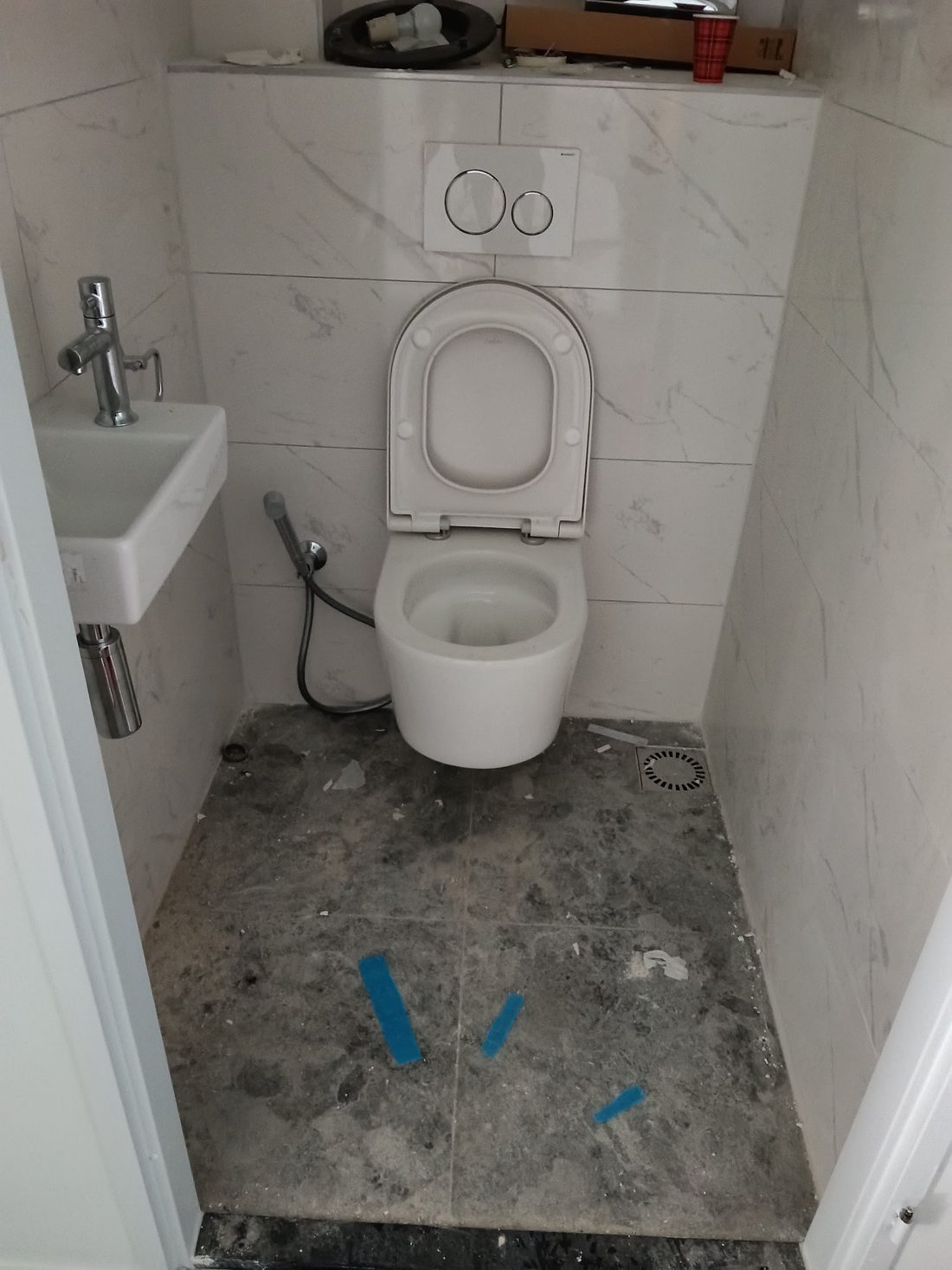Nieuw toilet met bouwstof, tape en puin op de vloer