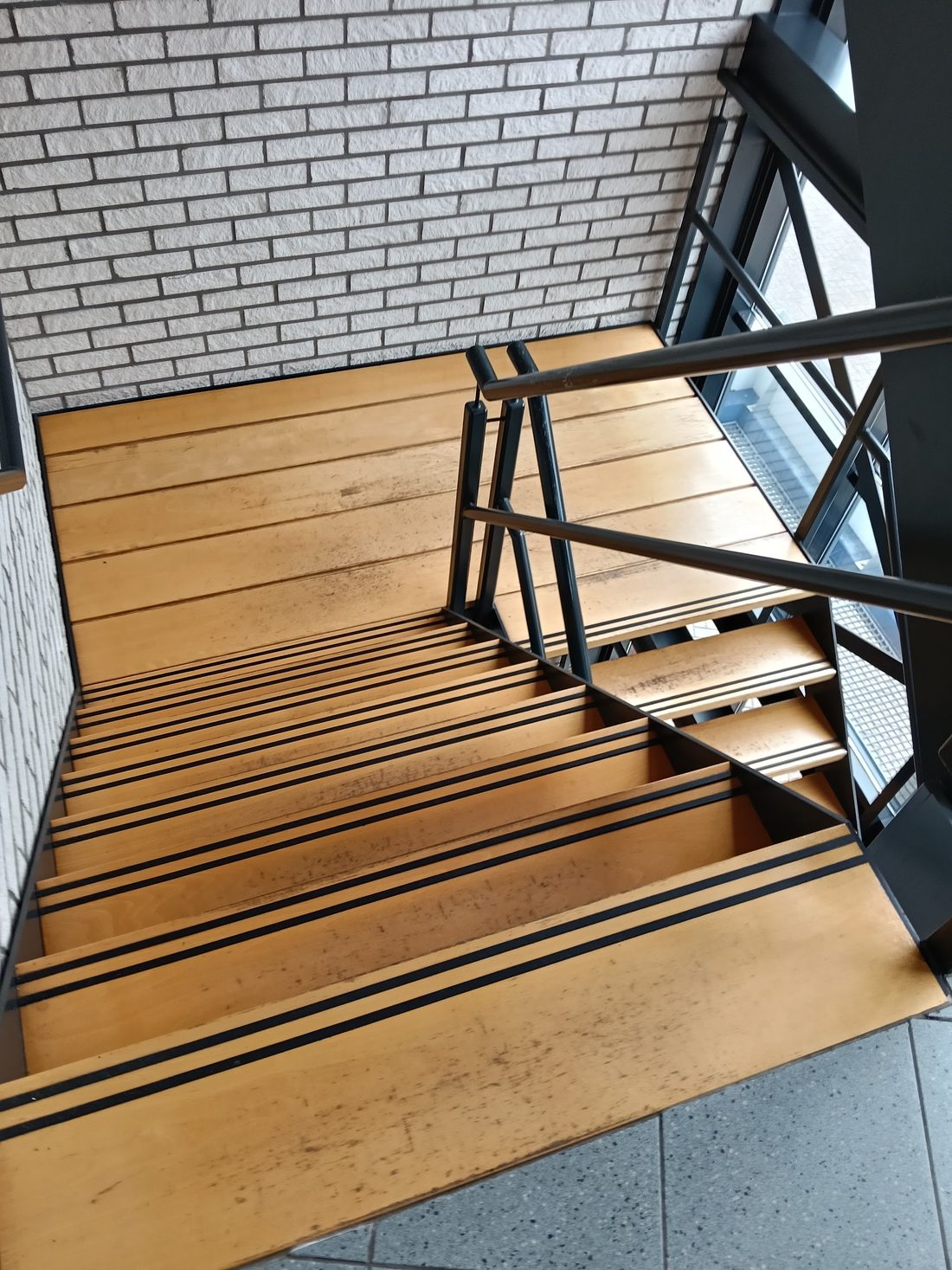 Trappenhuis met houten treden en een zwart stalen hekwerk