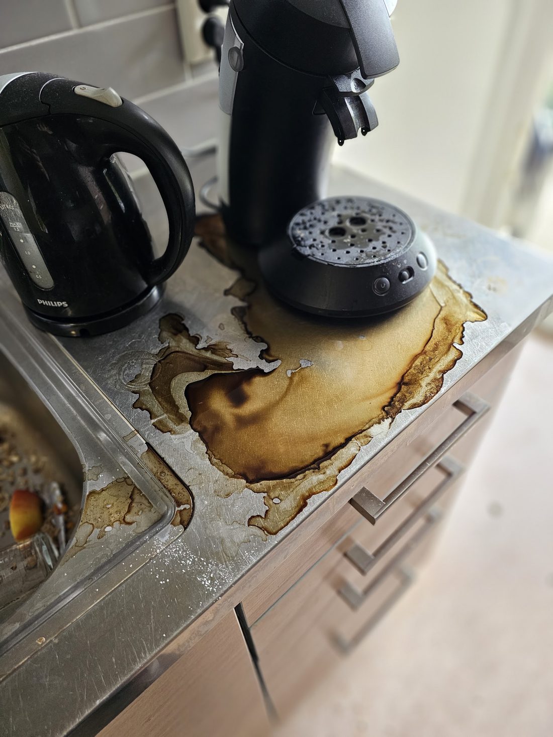 Roestvrijstalen aanrecht met ingebrande koffievlekken, voor het schoonmaken